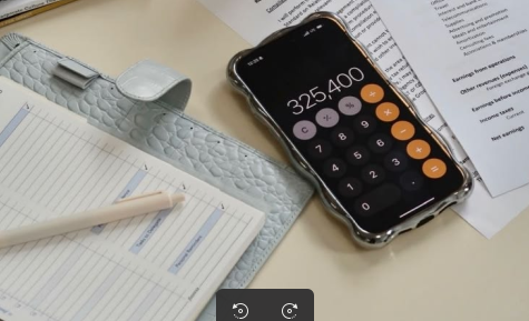 Calculadora junto a documentos de trabajo y una libreta de registro.